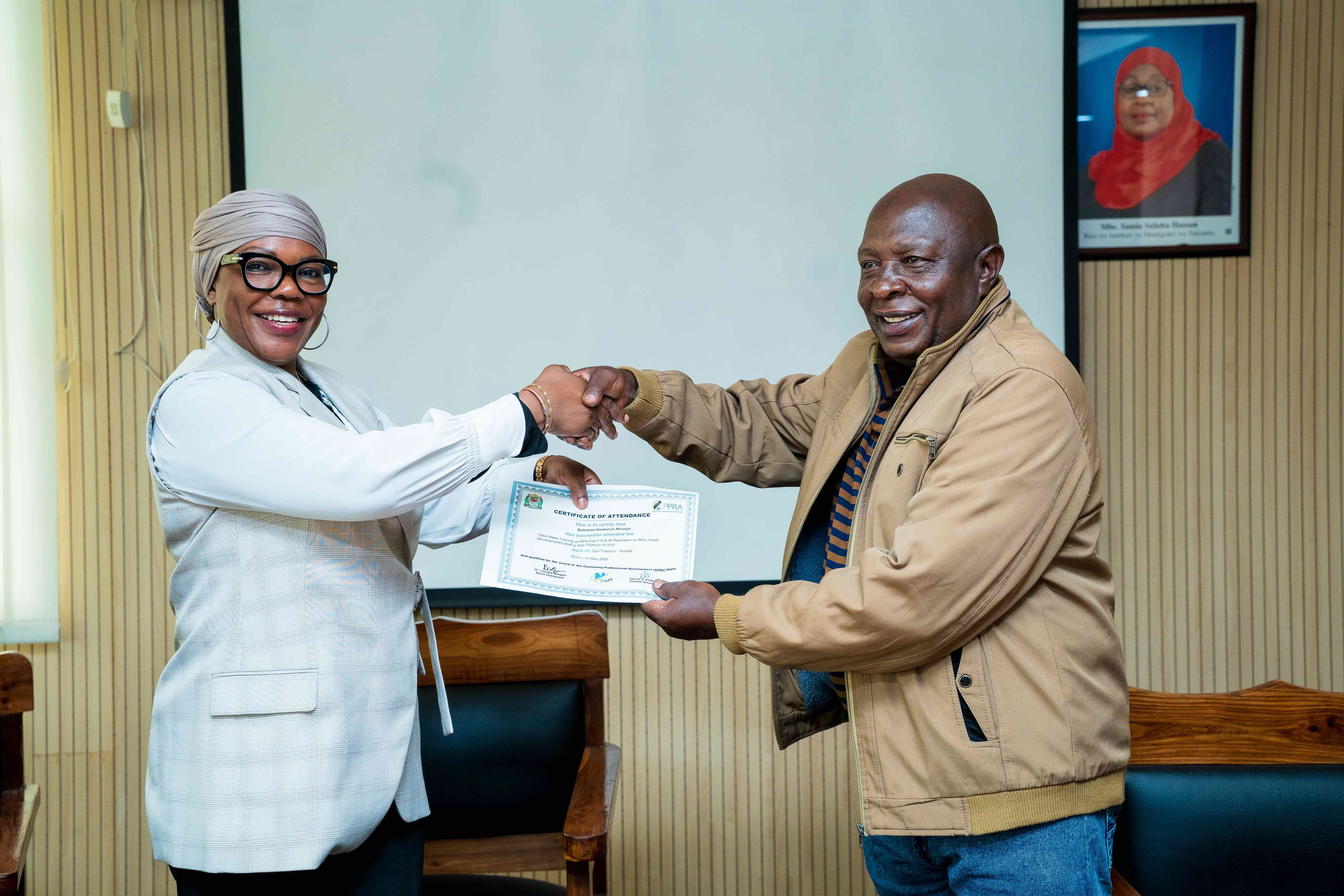 Mkurugenzi wa Utawala na menejimenti ya Rasilimali watu bi. Edith Semtengu akikabidhi cheti kwa Mkurugenzi Suleiman Mvunye
